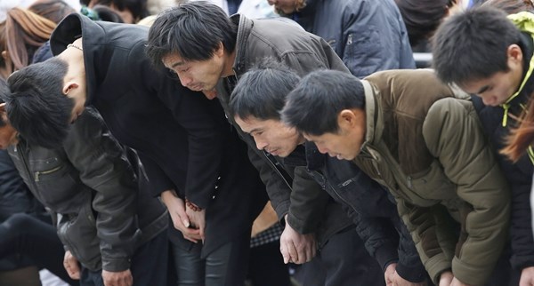 Relatives of victims bow as they attend a memorial ceremony for people who were killed in a stampede incident last Wednesday during a New Year's celebration on the Bund, in Shanghai