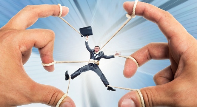 Stressed businessman governed by puppeteer hands