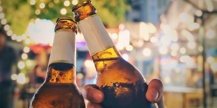 close-up-of-friends-toasting-beer-bottles-at-night-royalty-free-image-1596227691