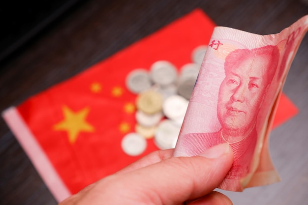 rmb-banknotes-chinese-yuan-money-hand-with-coins-china-flag-blurred-background_41472-1078