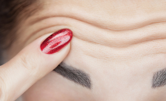 a-woman-shows-deep-wrinkles-on-her-forehead-aging-process-and-cosmological-skin-care