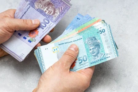 181149679-malaysian-money-held-in-both-hands-lots-of-ringgit-gray-background-financial-business-concept
