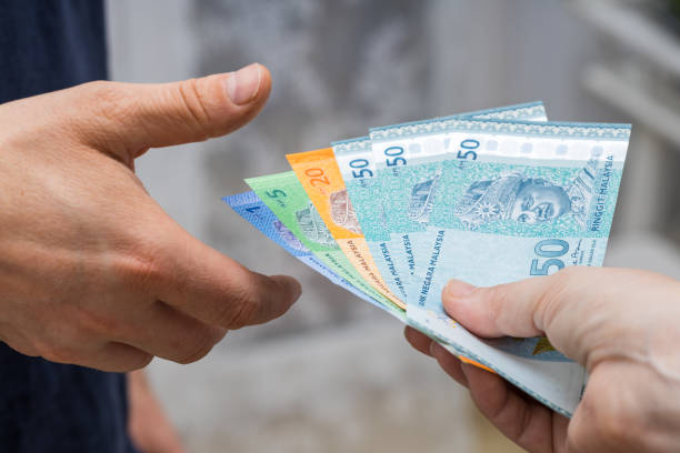 A file of Malaysian money, ringgit, given to another person from hand to hand