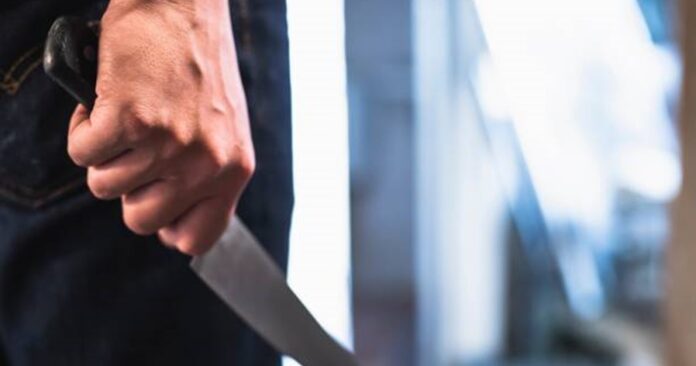 image of a robbers hands holding a knife in the shadows.