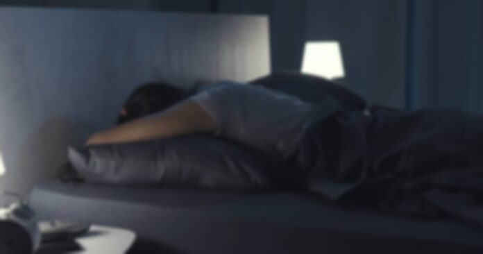 Woman sleeping in her bed at night, she is lying on her stomach