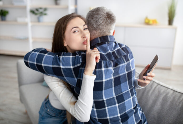 Beautiful,Mature,Woman,Hugging,Her,Husband,,Showing,Hush,Gesture,,Having