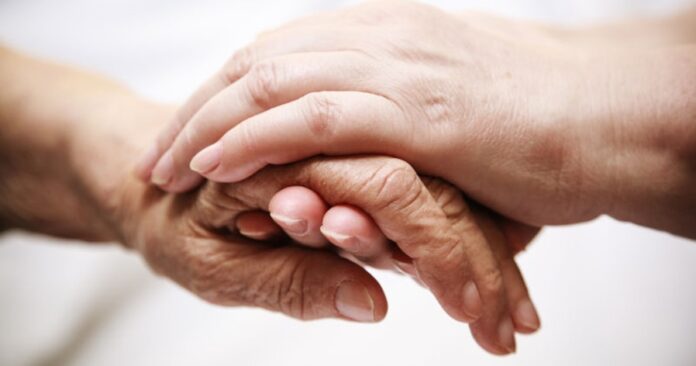adult helping senior in hospital